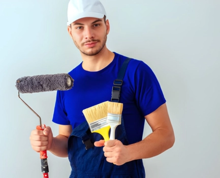 Painter holding a paint roller and brush for wall painting